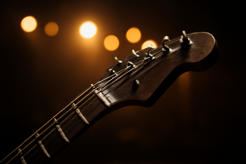 Senar gitar listrik terpasang di headstock dengan latar panggung gelap